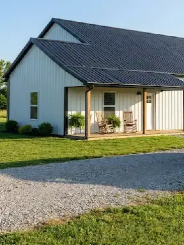 Exterior view of a small white farmhouse style barndominium with a black porch.